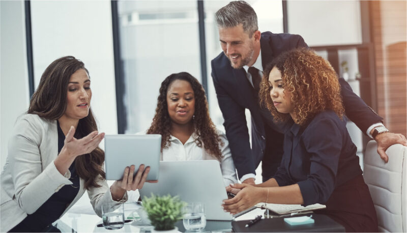 A group of four coworkers look over documents together