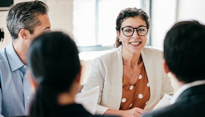 A woman smiles as she talks with her coworkers at a table