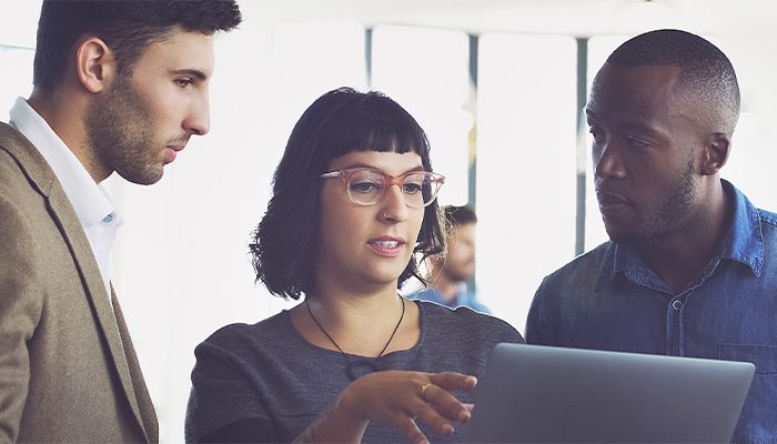 A woman shows her tablet screen to two male colleagues at the office